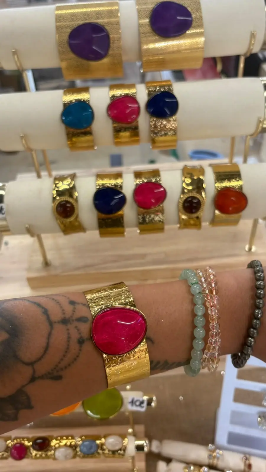 Manchettes dorées à cabochons de couleur, dont une portée au poignet