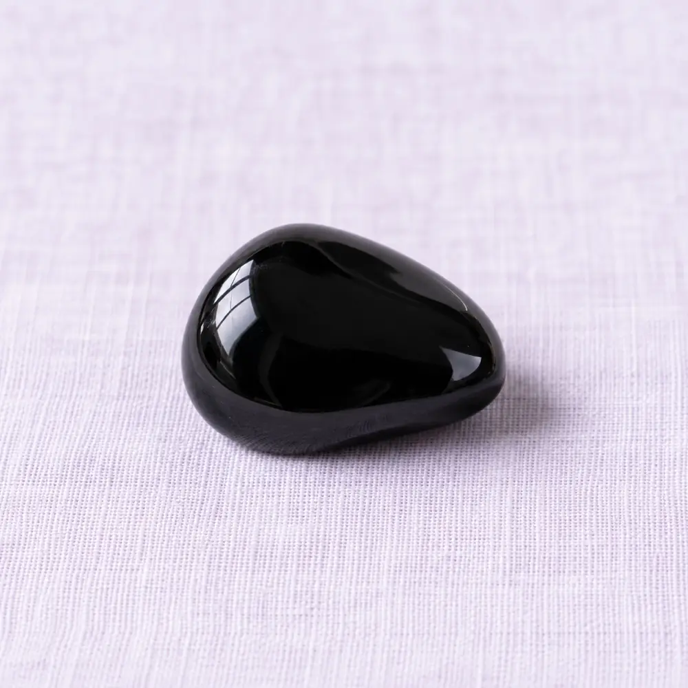 Obsidienne noire posée sur un lin lavande